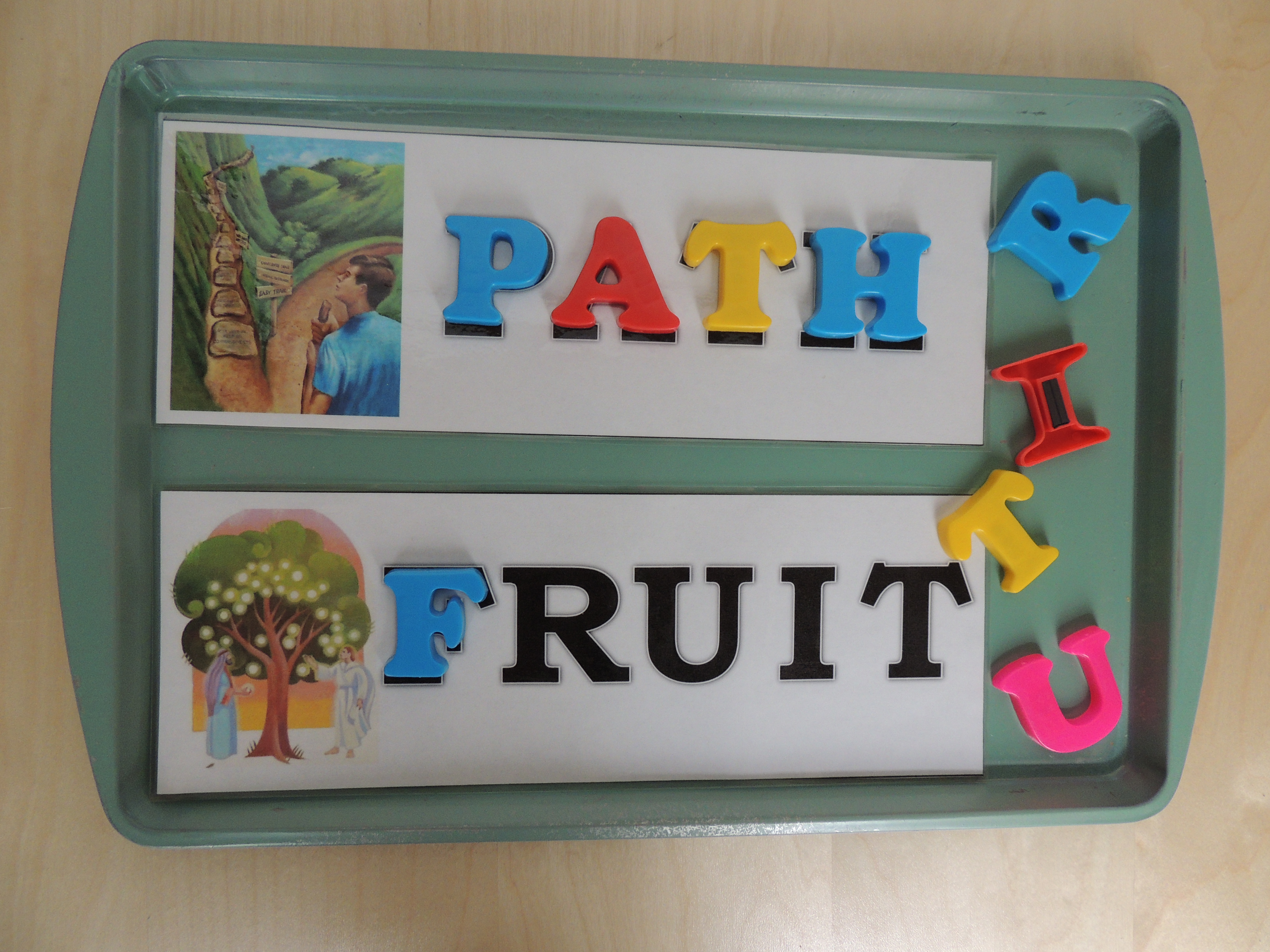 General Conference magnetic letter match activity with magnetic letters and gospel picture cards spelling PATH and FRUIT on a tray