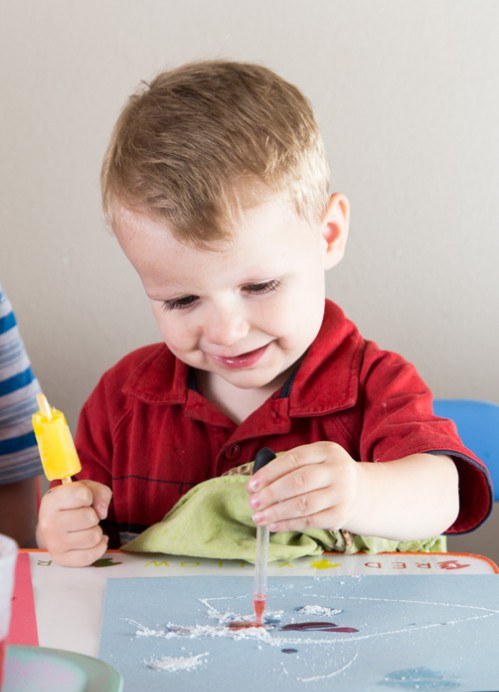 Toddler painting salt and glue fireworks, an easy 4th of July craft for preschoolers